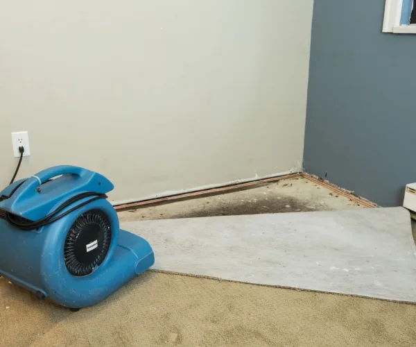 Water damaged walls and floors in house. Dehumidifier pointing at walls.